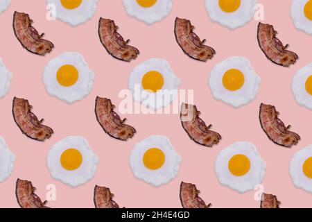 Motif composé d'œufs frits et de tranches de bacon croustillant sur fond rose vif.Concept petit déjeuner minimaliste et créatif.Vue de dessus.Pose à plat. Banque D'Images