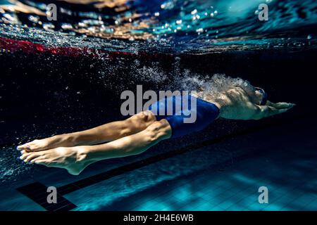 Prise de vue sous l'eau.Un entraînement masculin de nageur à la piscine, à l'intérieur.Vue sous-marine des détails des mouvements de natation. Banque D'Images