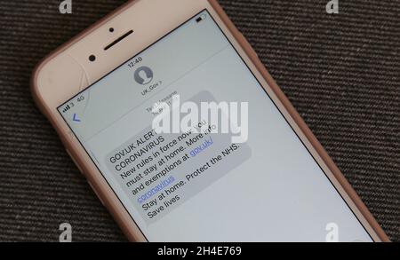 Un homme tient un téléphone portable affichant une alerte de message texte envoyée par le gouvernement avertissant que de nouvelles règles sont en vigueur dans tout le Royaume-Uni et que les gens doivent rester à la maison.Le message a été envoyé le matin après que le Premier ministre Boris Johnson ait mis le Royaume-Uni en quarantaine pour aider à freiner la propagation du coronavirus.Date de la photo: Mardi 24 mars 2020.Crédit photo : Isabel Infantes/Empics Entertainment Banque D'Images
