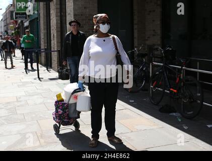 Une femme qui porte des EPI fait des files d'attente pour faire du shopping dans un supermarché de Dalston, Hackney, dans l'est de Londres, alors que le Royaume-Uni continue de se verrouiller pour aider à freiner la propagation du coronavirus.Date de la photo: Samedi 2 mai 2020. Banque D'Images