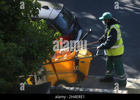 Un nettoyeur de rue portant un équipement personnel de protection (EPI) balaie une route dans le nord de Londres, après l'introduction de mesures pour mettre le pays hors de son confinement.Date de la photo: Mardi 19 mai 2020 Banque D'Images