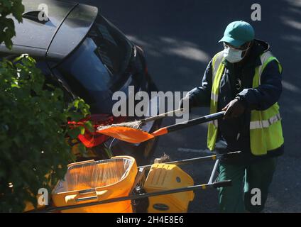 Un nettoyeur de rue portant un équipement personnel de protection (EPI) balaie une route dans le nord de Londres, après l'introduction de mesures pour mettre le pays hors de son confinement.Date de la photo: Mardi 19 mai 2020 Banque D'Images