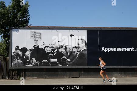 Un coureur passe devant un panneau d'affichage satirique par le groupe de campagne dirigé par des ânes montrant le Premier ministre britannique Boris Johnson superposé sur le visage du Premier ministre britannique d'apaisement de la Seconde Guerre mondiale Neville Chamberlain dans le nord de Londres, après l'introduction de mesures pour sortir le pays du confinement.Date de la photo: Lundi 25 mai 2020. Banque D'Images