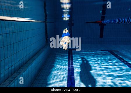 Prise de vue sous l'eau.Un entraînement masculin de nageur à la piscine, à l'intérieur.Vue sous-marine des détails des mouvements de natation. Banque D'Images