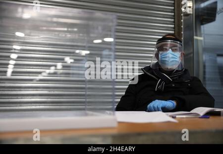 Un responsable du scrutin portant un masque chirurgical, un masque facial et des gants attend que les électeurs votent pour le Mercat del Ninot, qui a été converti en bureau de vote, à Barcelone lors des élections régionales en Catalogne, en Espagne.Date de la photo : 14 février 2021.Crédit photo devrait se lire: Isabel Infantes Banque D'Images