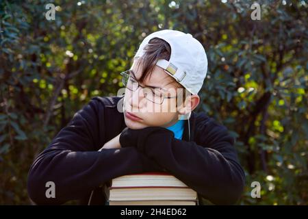 Triste adolescent avec un livre sur le fond de la nature Banque D'Images