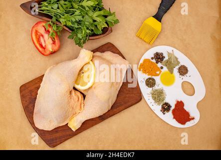 Des cuisses de poulet entières avec pasley, des épices et une brosse, sur un morceau de papier de cuisson.Peinture sur la viande crue concept. Banque D'Images