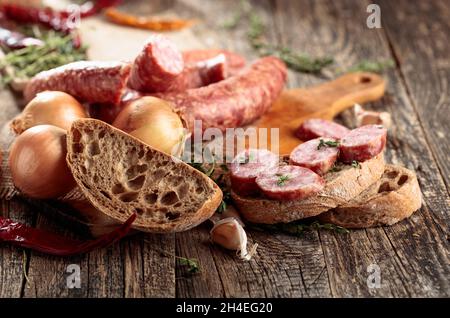 Sandwich à la saucisse sur une vieille table en bois.Saucisse séchée au thym, à l'oignon, à l'ail et au poivre. Banque D'Images