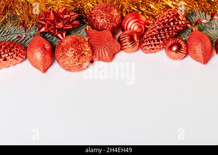 Composition festive de Noël avec branches de sapin ornées de guirlande dorée et décorations de Noël rouges brillantes sur fond blanc avec espace pour les copies Banque D'Images