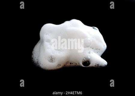 Mousse blanche avec bulles de savon, de nettoyant ou de shampooing isolée sur fond noir gros plan Banque D'Images