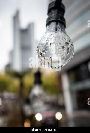 02 novembre 2021, Hessen, Francfort-sur-le-main: Les raindrops se sont installés sur une ampoule en face d'un café de rue.La tour du siège de la Commerzbank est visible en arrière-plan sur la gauche.Photo: Frank Rumpenhorst/dpa Banque D'Images