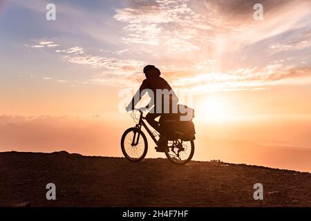 Vélo Mountain Rider avec sac à dos voyage sur fond de lever de soleil Banque D'Images