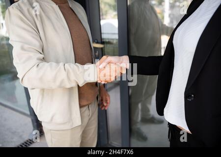 vue rognée de l'agent immobilier qui se serre les mains avec l'homme près de la nouvelle maison Banque D'Images