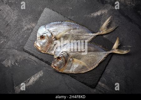 Vue de dessus de savoureux vomissant de poisson de mer salé séché ou Selena sur un plateau d'ardoise et un fond en marbre noir Banque D'Images