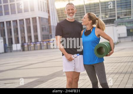 Heureux couple d'âge mûr, homme et femme dans les vêtements de sport se posant ensemble après l'entraînement du matin Banque D'Images
