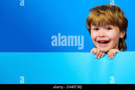 Enfant souriant avec planche vide.Petit garçon avec signe vierge pour le texte.Bannière publicitaire.Place pour votre publicité.Copier l'espace. Banque D'Images