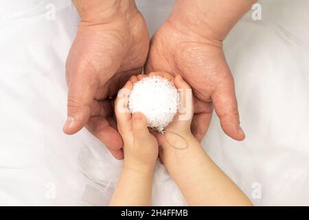 Père et fille tenant une boule de Noël décorative blanche avec soin et amour à la décoration d'un arbre de Noël.Nouvel an et veille de noël Banque D'Images