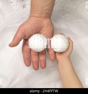 Père et fille tiennent deux boules de Noël décoratives blanches décorant l'arbre de Noël.Unité et famille du nouvel an et de la veille de Noël Banque D'Images