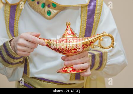 Un homme dans les vêtements d'Aladdin . Une personne tient dans sa main lampe d'or réaliste d'Aladdin . Olds dans ses mains la lampe magique d'Aladdin. Tenant un vieux Banque D'Images