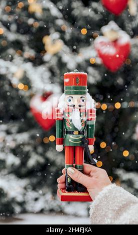 Gros plan perspective personnelle d'une femme tenant un soldat de casse-noisette en bois devant l'arbre de noël Banque D'Images