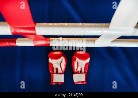 Gros plan de gants de boxe rouges sur le sol d'un anneau de boxe bleu. Banque D'Images