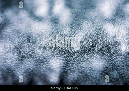 Faire fondre de petits morceaux de glace sur le verre de la fenêtre sous forme de écailles.Arrière-plan abstrait.Thème froid et temps.Mise au point sélective Banque D'Images