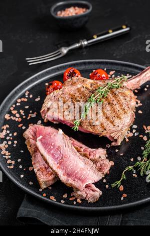 Barbecue de côtes de bœuf Tomahawk (veau) sur une assiette de sel rose.Arrière-plan noir.Vue de dessus Banque D'Images