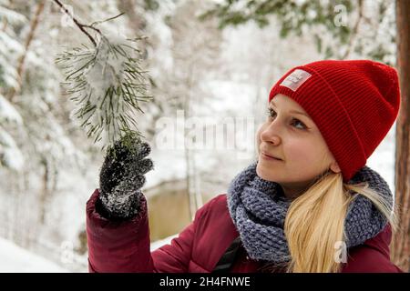 Portrait d'une fille dans la forêt d'hiver et regarder une branche dans la neige. Haute qualité Banque D'Images