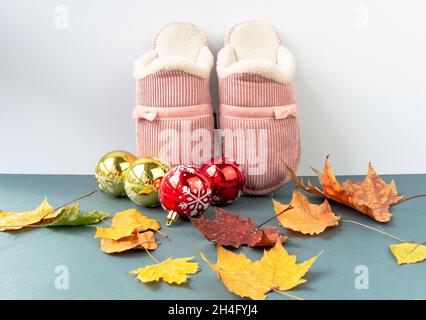 Pantoufles chaudes et confortables avec feuilles jaunes et décoration de Noël sur fond vert. Couleur rose. Banque D'Images