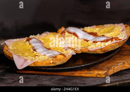 Gros plan de deux moitiés d'un pain avec fromage et bacon sur une plaque ronde pour faire un hamburger Banque D'Images