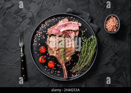 Barbecue de côtes de bœuf Tomahawk (veau) sur une assiette de sel rose.Arrière-plan noir.Vue de dessus Banque D'Images