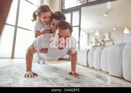 Un homme heureux qui se fait pousser avec des enfants à la maison Banque D'Images