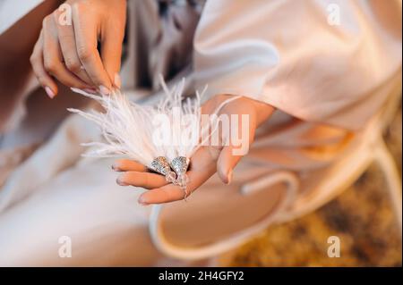 Boucles d'oreilles avec frange blanche dans les mains de la mariée à un mariage en Italie.mariage boucles d'oreilles cheveux blanches en Toscane. Banque D'Images