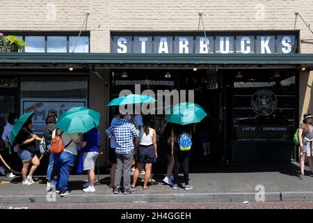 Les clients portant des parasols verts fournis par le café Starbucks se trouvant à l'extérieur du café Starbucks d'origine.Seattle.Washington.USA Banque D'Images