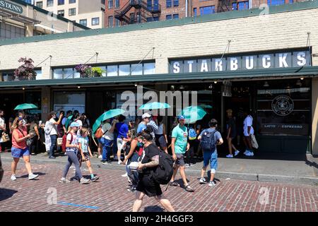 Les clients portant des parasols verts fournis par le café Starbucks se trouvant à l'extérieur du café Starbucks d'origine.Seattle.Washington.USA Banque D'Images