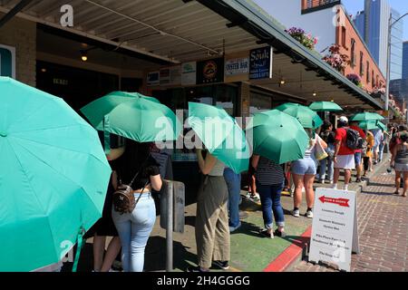 Les clients portant des parasols verts fournis par le café Starbucks se trouvant à l'extérieur du café Starbucks d'origine.Seattle.Washington.USA Banque D'Images