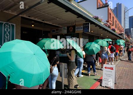 Les clients portant des parasols verts fournis par le café Starbucks se trouvant à l'extérieur du café Starbucks d'origine.Seattle.Washington.USA Banque D'Images