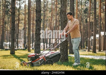 Homme marchant sur l'herbe avec une tondeuse Banque D'Images