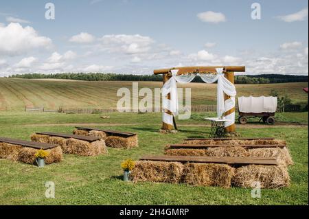 Cérémonie de mariage dans la rue dans le champ du village.décor avec des haystacks et un chariot pour un mariage.rustique fête de mariage Banque D'Images