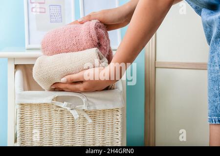 Femme mettant des vêtements propres dans le panier en osier à la maison, gros plan Banque D'Images