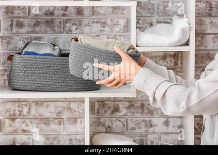 Femme mettant le panier avec des vêtements propres sur la tablette, gros plan Banque D'Images
