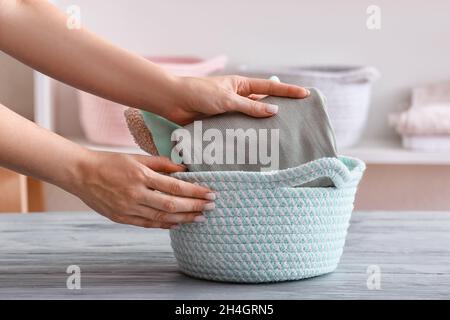 Femme mettant des vêtements propres dans le panier sur la table, gros plan Banque D'Images