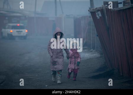 Une mère marche sa fille à la maternelle pendant une matinée très polluée dans la ville, Oulan-Bator, le 15 janvier 2019.À mesure que la qualité de l'air en milieu urbain diminue Banque D'Images