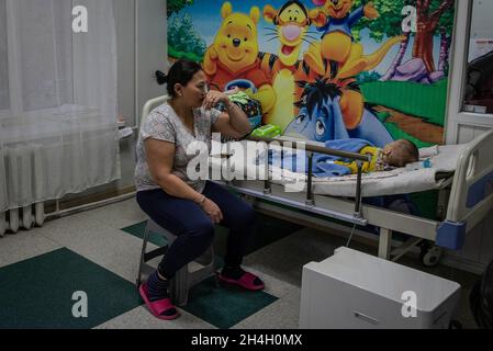 Une mère regarde son bébé garçon souffrant de complications respiratoires dans une unité d'urgence pédiatrique de l'un des hôpitaux de la capitale Banque D'Images