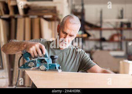 Homme planant du bois avec un rabot à main Banque D'Images