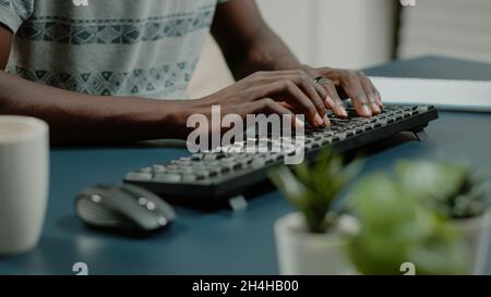 Gros plan des mains à l'aide du clavier de l'ordinateur et en écoutant de la musique pour travailler à distance.Homme dansant et chantant tout en travaillant à la maison avec la technologie.Travailleur s'amusant à son bureau Banque D'Images