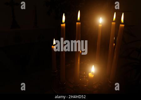 Bougies allumées sur fond sombre dans le temple. Banque D'Images