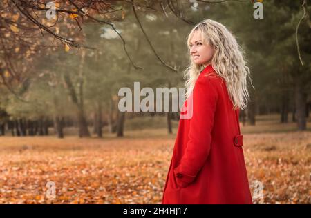 belle jeune fille dans un manteau rouge sur une promenade Banque D'Images