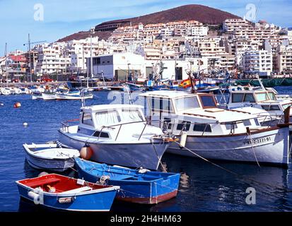 Bateaux de pêche dans le port avec des bâtiments de ville à l'arrière, Los Cristianos, Tenerife, Espagne. Banque D'Images