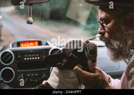 Un homme chaleureusement habillé appréciant le camion moderne avec son chien assis dans le siège du conducteur.Concept « voyager avec des animaux ». Banque D'Images